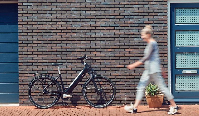 Frau und Prophete E-Bike an eine Mauer gelehnt